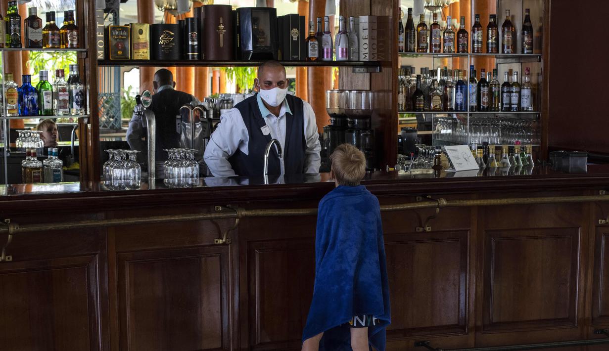 Seorang turis muda meminta minuman ringan kepada pelayan di hotel Iberostar Selection Varadero di Varadero, Kuba, Rabu (29/9/2021). Pihak berwenang di Kuba mulai melonggarkan pembatasan COVID-19 di beberapa kota seperti Havana dan Varadero. (AP Photo/Ramon Espinosa)
