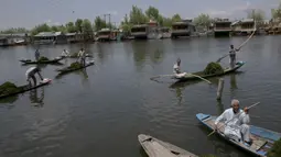 Para tukang perahu yang dipekerjakan oleh Pemerintah Jammu dan Kashmir menyingkirkan gulma dari Danau Dal di Srinagar, Kashmir, India, Rabu (22/7/2020). Danau Dal terkenal dengan airnya yang jernih dan tenang. (AP Photo/Dar Yasin)