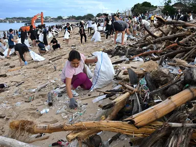 Para relawan membersihkan sampah plastik dan lainnya yang terdampar di pantai Kedonganan, Kabupaten Badung, Bali, pada Sabtu 4 Januari 2025. (SONNY TUMBELAKA/AFP)