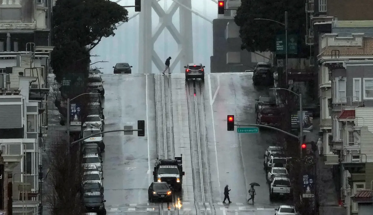 Pejalan kaki melintasi California Street di San Francisco, Amerika Serikat, 24 Februari 2023. California dan bagian lain di Barat menghadapi salju lebat dan hujan dari badai musim dingin terbaru yang melanda Amerika Serikat. (AP Photo/Jeff Chiu)