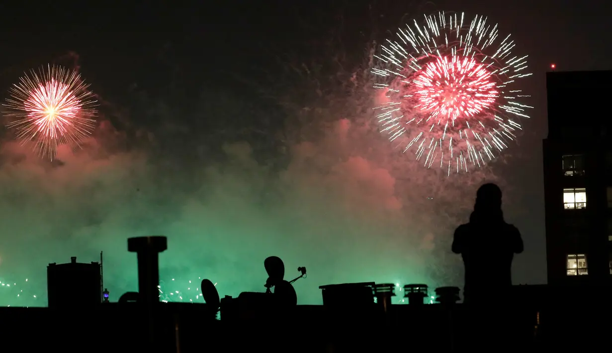 Seorang pria mengambil gambar kembang api yang meledak di udara pada perayaan Hari Kemerdekaan Amerika Serikat di New York City, Rabu (4/7).  AS merayakan hari kemerdekaan yang jatuh pada 4 Juli atau dikenal Independence Day 4th July. (AP/Julio Cortez)