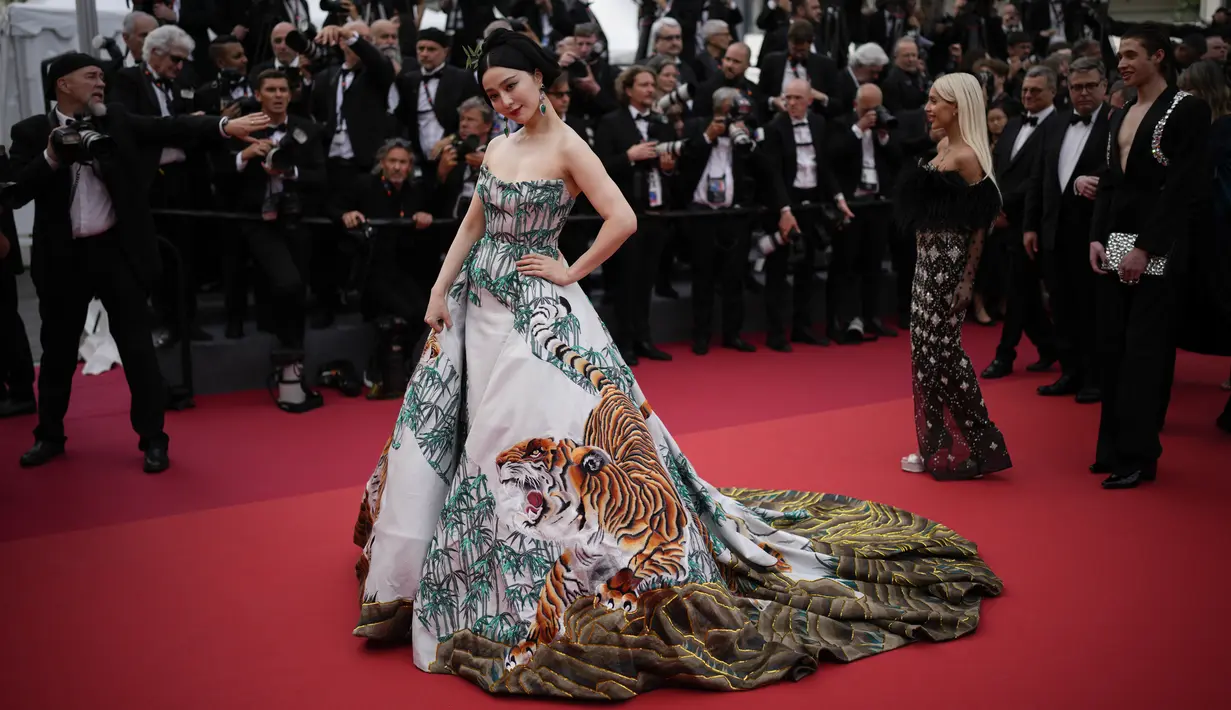 <p>Fan mengenakan gaun Christoper Bu dengan kereta menyapu dan cetakan yang terinspirasi hutan dengan gambar dedaunan, kulit pohon, dan beberapa harimau yang tampak berjalan keluar dari gaun itu. (Photo by Joel C Ryan/Invision/AP)</p>