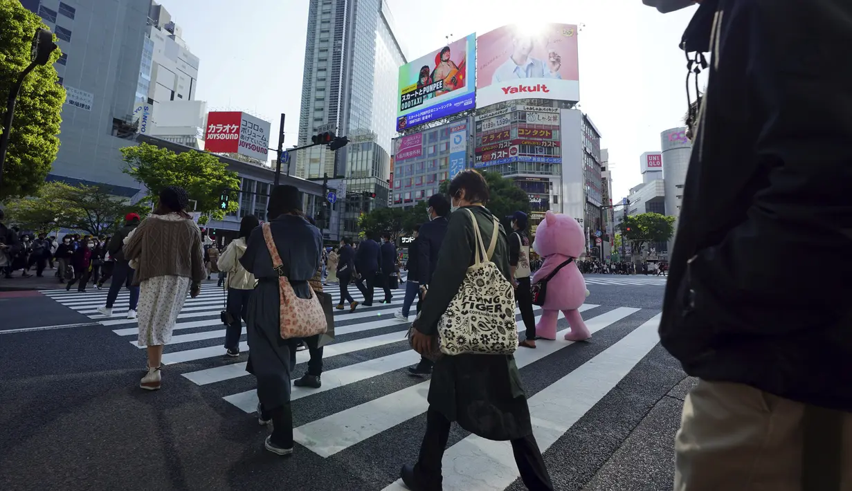 Orang-orang yang mengenakan masker pelindung untuk membantu mengekang penyebaran virus corona COVID-19 menyeberang jalan di Distrik Shibuya, Tokyo, Jepang, Rabu (7/4/2021). Tokyo mengonfirmasi lebih dari 550 kasus COVID-19 baru pada 7 April 2021. (AP Photo/Eugene Hoshiko)