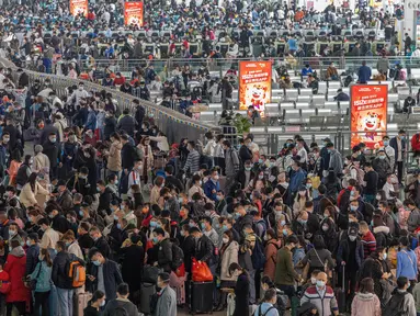 Pelancong yang mengenakan masker mengantre kereta di sebuah stasiun di Guangzhou di Provinsi Guangdong, China, Jumat (28/1/2022). Warga China bepergian ke kampung halaman mereka untuk Tahun Baru Imlek yang merupakan salah satu mobilitas manusia terbesar sedunia. (Chinatopix via AP)