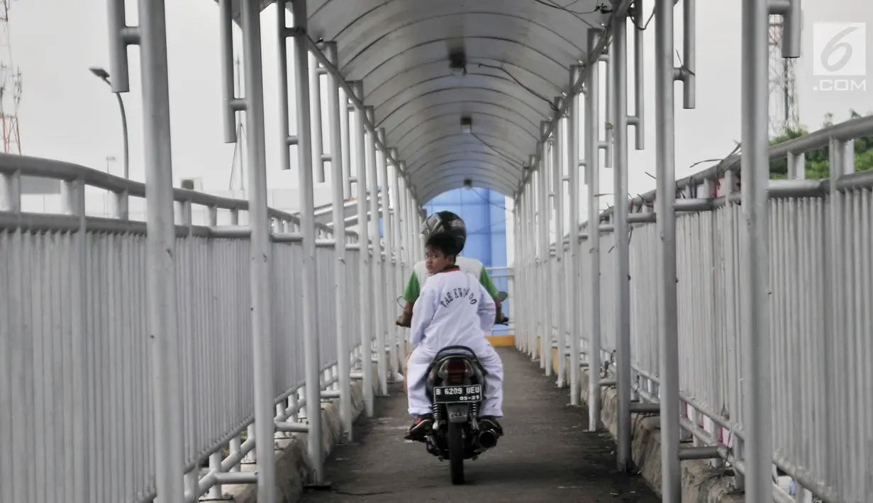 Pengendara sepeda motor melintasi JPO di Jalan Yos Sudarso, Jakarta, Senin (12/11). Aksi nekat yang dilakukan para pengendara sepeda motor demi mempersingkat rute jalan tersebut dapat membahayakan diri mereka sendiri. (Merdeka.com/Iqbal S. Nugroho)