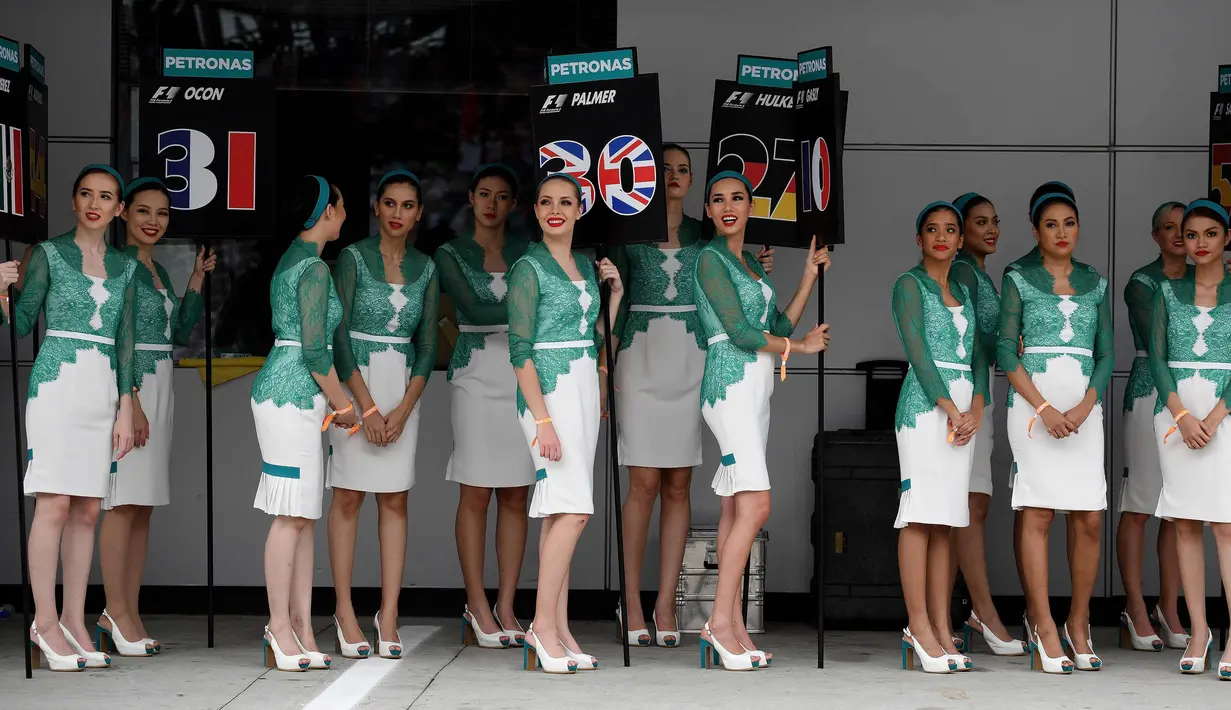 Sejumlah grid girl atau gadis pendamping bersiap untuk mendampingi para pembalap sebelum dimulainya Grand Prix Formula 1 Malaysia di Sepang (1/10). Para gadis payung ini terlihat seksi dengan baju ketat yang dikenakannnya. (AFP Photo/Manan Vatsyayana)
