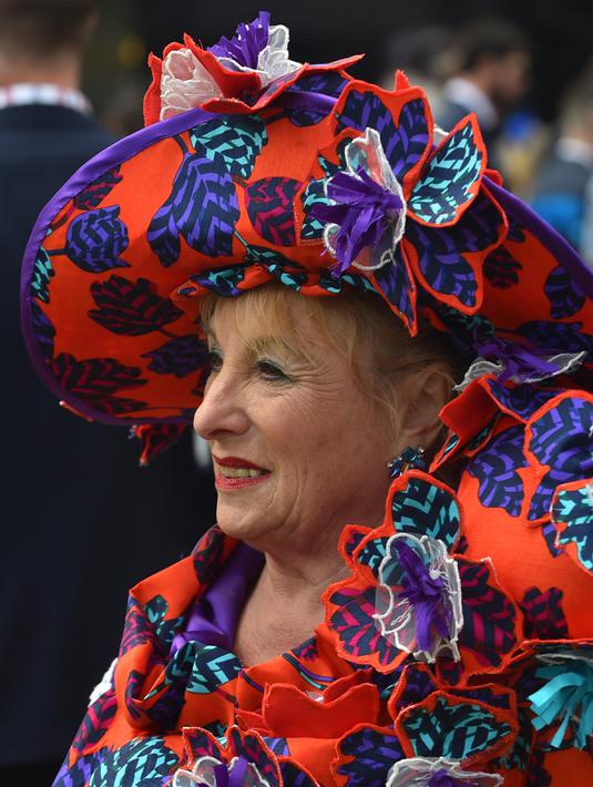 Wanita paruh baya memakai hiasan kepala lengkap dengan bajunya yang bercorak bunga saat menghadiri balap kuda Melbourne di arena pacuan kuda Flemington Racecourse di Melbourne, Australia (1/11). (AFP/Paul Crock)