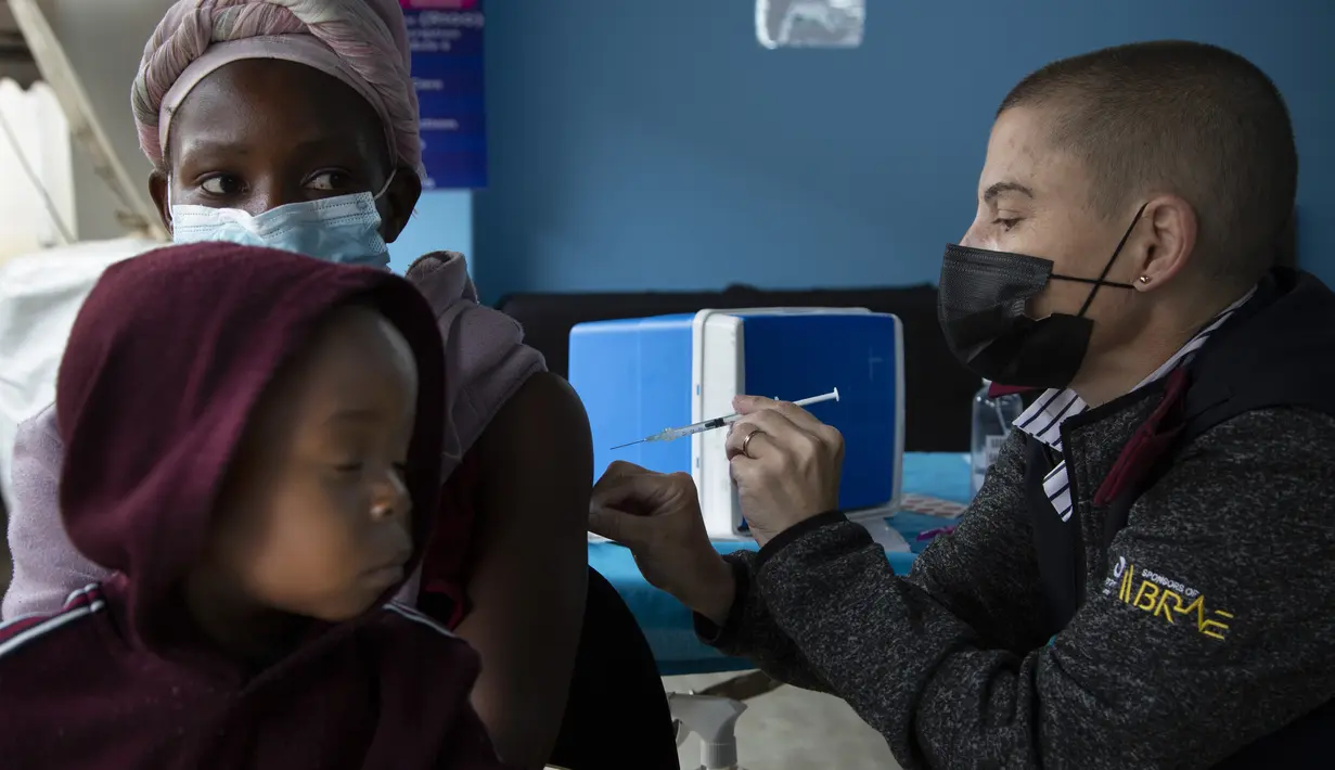 Seorang wanita, dengan anak di pangkuannya, divaksin COVID-19 di sebuah lokasi dekat Johannesburg, Rabu (8/12/2021). Kasus Omicron telah dikonfirmasi setidaknya di sembilan negara Afrika, dengan Afrika Selatan tetap menjadi episenter awal ditemukannya varian baru tersebut. (AP Photo/Denis Farrell)