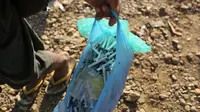 Seorang penambang mengumpulkan jarum suntik yang telah digunakan di Tambang batu giok di Hpakant, Myanmar, 29 November 2015. Kecanduan narkotika sudah merabak pada penambang batu giok. (REUTERS/Soe Zeya Tun)