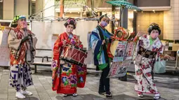 Orang-orang yang mengenakan kimono berbaris di jalan saat mereka mengiklankan pekan raya akhir tahun di Distrik Nihonbashi, Tokyo, Jepang, 26 Desember 2022. Tak hanya menyuguhkan pemandangan indah dan makanan yang lezat, Jepang juga menjadi negara yang tepat untuk merayakan tahun baru. (Yuichi YAMAZAKI/AFP)