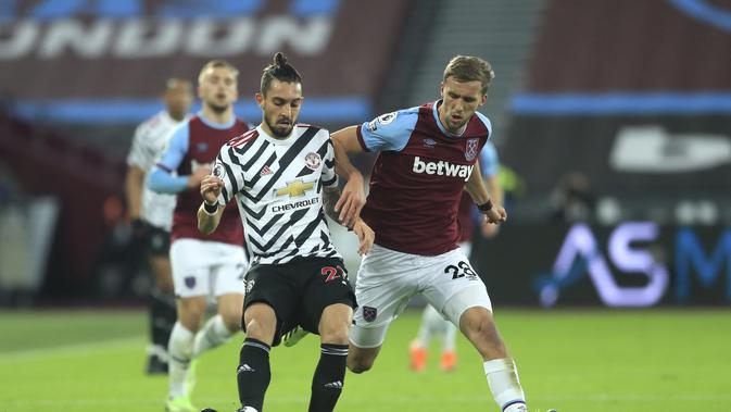 Bek Manchester United, Alex Telles mengumpan bola dari kawalan gelandang West Ham, Tomas Soucek pada pertandingan lanjutan Liga Inggris di stadion London di London, Inggris, Minggu (6/12/2020). MU menang 3-1 atas West Ham. (Adam Davy / Pool via AP)