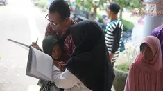 Seorang ayah mengisi data informasi setelah bertemu anaknya yang sempat hilang di Taman Margasatwa Ragunan, Jakarta, Kamis (6/6/2019). Membeludaknya pengunjung, membuat banyak orang yang memadati pusat informasi untuk mencari anggota keluarga serta barang berharga. (Liputan6.com/Immanuel Antonius)