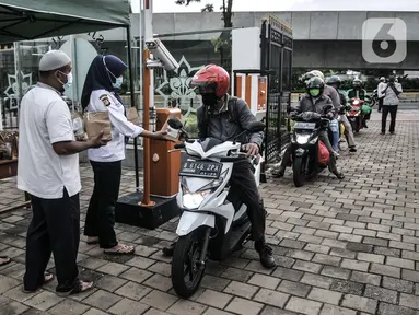 Petugas membagikan takjil kepada pengendara secara drive thru di Kompleks Masjid Al-Azhar, Jakarta, Selasa (13/4/2021). Pengelola Masjid Al-Azhar menyiapkan 500 bungkus takjil per hari yang dibagikan secara drive thru guna mencegah penyebaran COVID-19. (merdeka.com/Iqbal S. Nugroho)