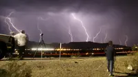 Fotografer saat mengabadikan kilatan petir yang terlihat dari bandara Daggett, Barstow, California, Rabu (1/7/2015) waktu setempat. Cuaca ekstrim yang terjadi mengakibatkan hujan badai di kawasan tersebut. (REUTERS/Gene Blevins)