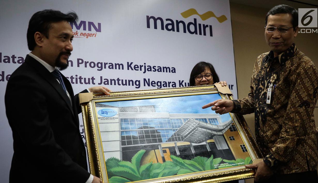 Chief Operating Officer IJN Kuala Lumpur Akmal Arief Mohamed Fauzi memberi lukisan kepada Direktur Retail Banking Bank Mandiri Tardi saat penandatanganan perjanjian kerjasama di Jakarta, Rabu (6/9). (Liputan6.com/Angga Yuniar)