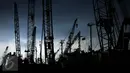 Siluet buruh yang sedang melakuan bongkar muat dibantu dengan alat berat di Pelabuhan Sunda Kelapa, Jakarta, Selasa (2/5). (Liputan6.com/Johan Tallo)