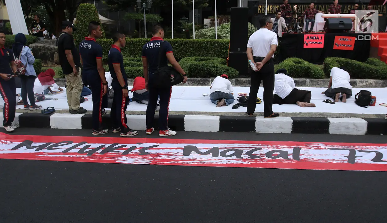 Peserta melukis di atas kanvas selebar 300 meter dalam acara lomba melukis massal di depan Kemenkumham, Jakarta, Minggu (13/8). Hadiah yang ditawarkan untuk kategori lomba lukis massal ini dari Rp10 juta hingga Rp 2 juta. (Liputan6.com/Herman Zakharia)