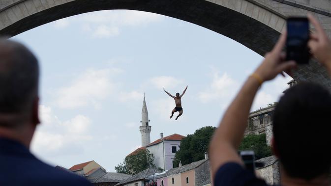 Seorang peserta melompat dari Jembatan Old Mostar pada kompetisi menyelam tradisional ke-452 di Mostar, Bosnia, 29 Juli 2018. Ini merupakan kompetisi selam tahunan yang menjadi salah satu daya tarik Bosnia dan berlangsung sejak abad ke 17. (AP/Amel Emric)