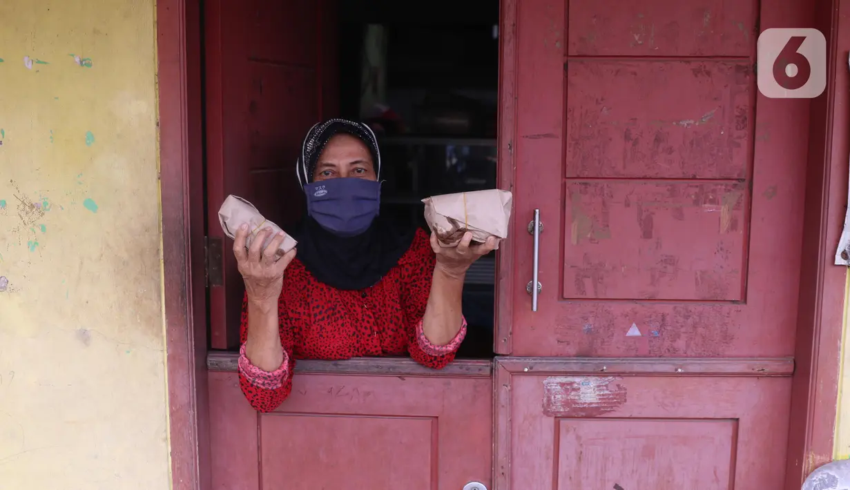 Warga terdampak Covid-19 menunjukkan nasi bungkus di di RW 03, Kelurahan Gandasari, Kecamatan Jatiuwung, Kota Tangerang, Jumat (11/6/2021).  Dampak penerepan lockdown membuat warga sekitar yang sehat melakukan aksi bersama untuk menyuplai makanan.  (Liputan6.com/Angga Yuniar)