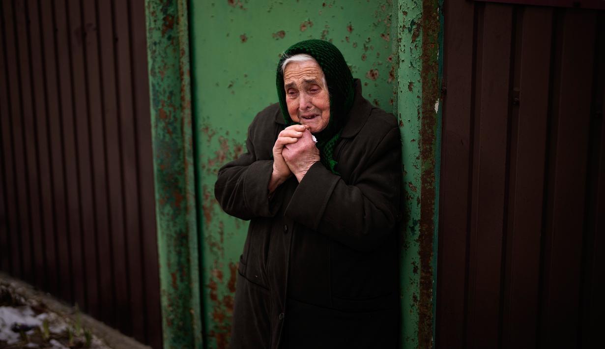 Olha Petrenko (84) menangis saat peti mati Oleksandr Maksymenko (38) lewat pada pemakamannya di kampung halamannya di Kniazhychi, sebelah timur Kyiv, Ukraina, 13 Februari 2023. Oleksandr Maksymenko, seorang warga sipil yang menjadi sukarelawan di angkatan bersenjata Ukraina, tewas dalam pertempuran di daerah Bakhmut. (AP Photo/Emilio Morenatti)