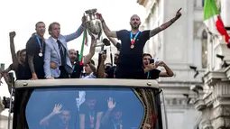 Pelatih Italia Roberto Mancini dan bek Leonardo Bonucci memegang trofi di atas bus terbuka saat perayaan juara Euro 2020 di Roma, Senin (12/7/2021). Italia mengalahkan Inggris 3-2 dalam adu penalti setelah bermain imbang 1-1 pada final Euro 2020. (Roberto Monaldo/Lapresse via AP)