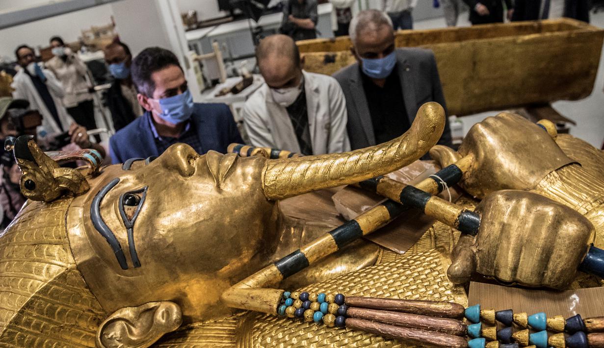 Para arkeolog merestorasi sarkofagus atau peti mati emas Firaun Tutankhamun di laboratorium restorasi Grand Egyptian Museum (GEM), Giza, Mesir, Senin (13/4/2020). Firaun Tutankhamun merupakan Raja Mesir Kuno yang memerintah antara tahun 1342-1325 SM. (Khaled DESOUKI AFP)