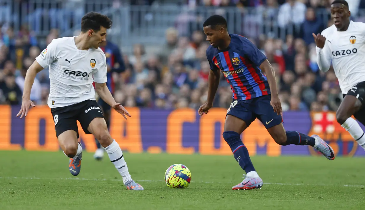 Penyerang Barcelona, Ansu Fati (tengah) berusaha melewati pemain Valencia, Ilaix Moriba selama pertandingan lanjutan La Liga Spanyol di stadion Camp Nou, Spanyol, Minggu (5/3/2023). Berkat kemenangan ini, Barcelona kini mengumpulkan 62 poin di puncak klasemen Liga Spanyol. (AP Photo/Joan Monfort)