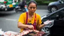 Seorang wanita memasak sate di gerobaknya di samping jalan di Bangkok, Thailand (20/9). Kota Bangkok, terkenal sebagai salah satu street food capital alias kota yang identik dengan makanan pinggir jalan. (AFP Photo/Jewel Samad)