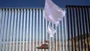 Pemandangan pagar perbatasan antara Meksiko dan Amerika Serikat yang dihiasi seni instalasi kontemporer "Tu huella es el camino, tu bandera es de paz" di Playas de Tijuana, Meksiko (7/10). (AFP Photo/Guillermo Arias)