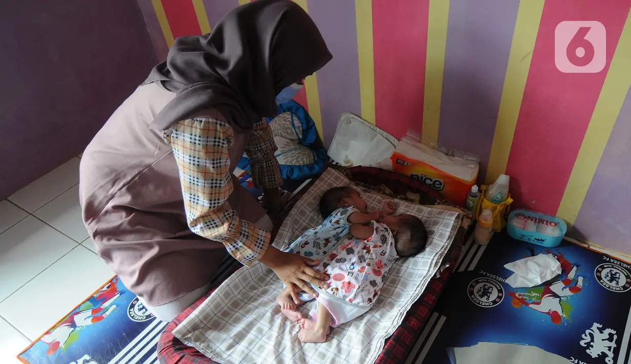 Evi Susanti menjaga putrinya kembarnya, Queenetha Zaina dan Queenesha Zahira di rumahnya di Perumahan Permata Indah Blok W No. 18 RT 18/03, Desa Bojongraharja, Kabupaten Sukabumi, Sabtu (14/08/2021). Bayi kembar siam berusia 1,5 bulan ini memiliki dua jantung dan satu hati. (merdeka.com/Arie Basuki)