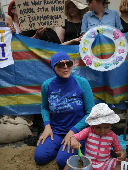 Seorang pengunjuk rasa mengenakan burkini di pantai buatan yang dibuat di depan kedutaan Prancis di London, Inggris, Kamis (25/8). Sejumlah wanita memprotes larangan burkini yang diberlakukan di beberapa kota pesisir di Prancis. (REUTERS/Neil Hall)