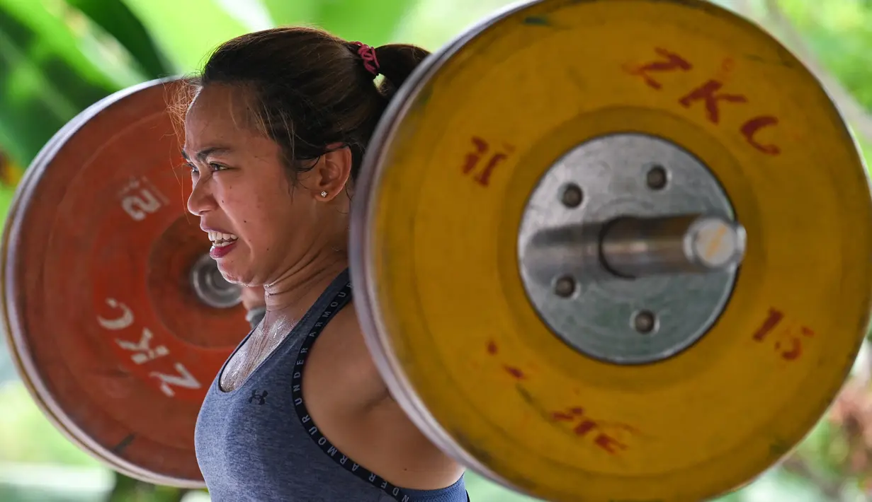 Atlet angkat besi Olimpiade Filipina, Hidilyn Diaz mengangkat beban saat berlatih di Jasin, kota Malaka, pada 21 Mei 2021. Diaz yang terpaksa tinggal di Malaysia bertekad situasi tidak akan menghalangi cita-citanya untuk menjadi peraih medali emas Olimpiade pertama dari Filipina. (Mohd RASFAN/AFP)
