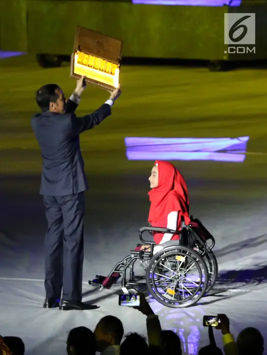 Presiden RI, Joko Widodo (kiri) menerima plakat dari penyandang disabilitas saat malam pembukaan Asian Para Games 2018 di SUGBK, Jakarta, Sabtu (6/10). Asian Para Games 2018 berlangsung 6-13 Oktober. (Liputan6.com/Helmi Fithriansyah)