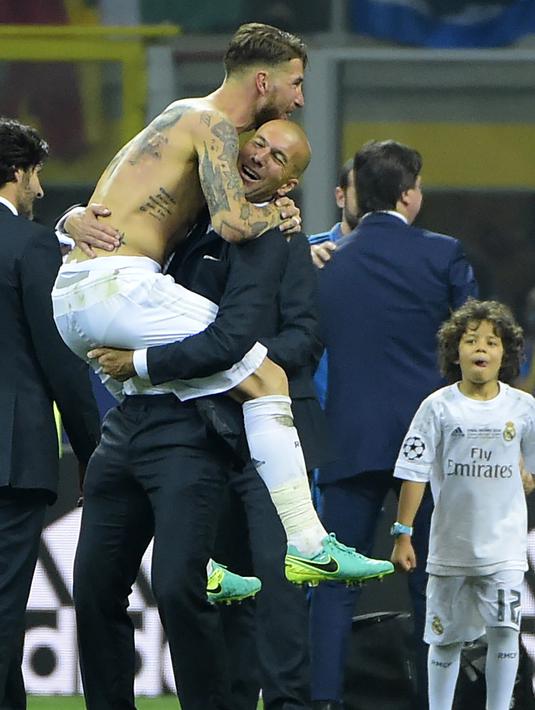 Sergio Ramos melompat sambil memeluk Zidane saat meraih trofi Liga Champions di San Siro Stadium, Milan, (28/5/2016). Zinedine mundur sebagai pelatih Madrid 31 Mei 2018. (AFP/Olivier Morin)