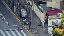 Seorang pekerja yang mengenakan alat pelindung diri berdiri di sebelah pintu masuk ke lingkungan saat lockdown tahap kedua akibat COVID-19 di Distrik Jing'an, Shanghai, China, Rabu (6/4/2022). (Hector RETAMAL/AFP)