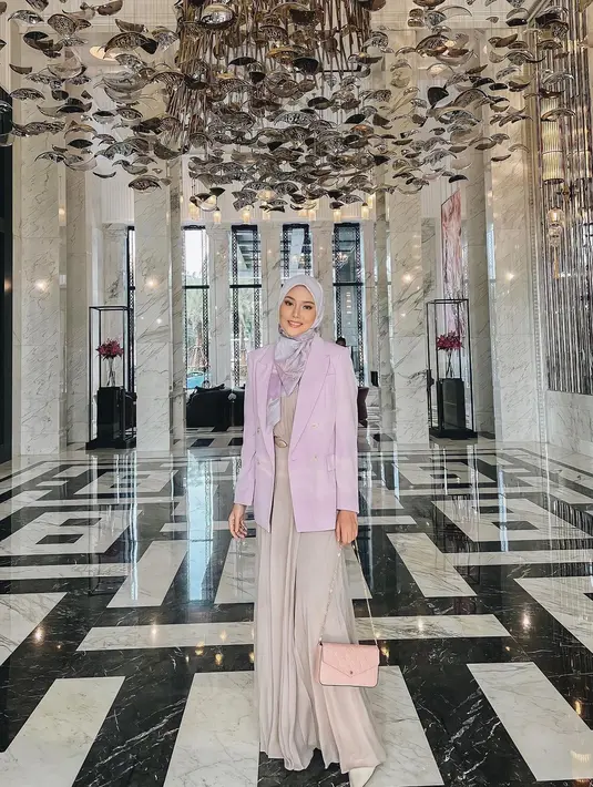 Tetap modis dengan modest wear. Dara Arafah terlihat memadukan gamis nuansa warna krem dengan blazer ungu dan hijab bermotif warna senada. (Instagram/ daraarafah)..