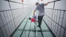 Seorang turis memegang anaknya saat berjalan di jembatan gantung dari kaca di pegunungan Shinuizhai, Provinsi Hunan, Tiongkok, 6 Oktober 2015. Jembatan dengan panjang 300 m dan tinggi 180 m ini kembali dibuka setelah direnovasi. (AFP/Johannes Eisele)