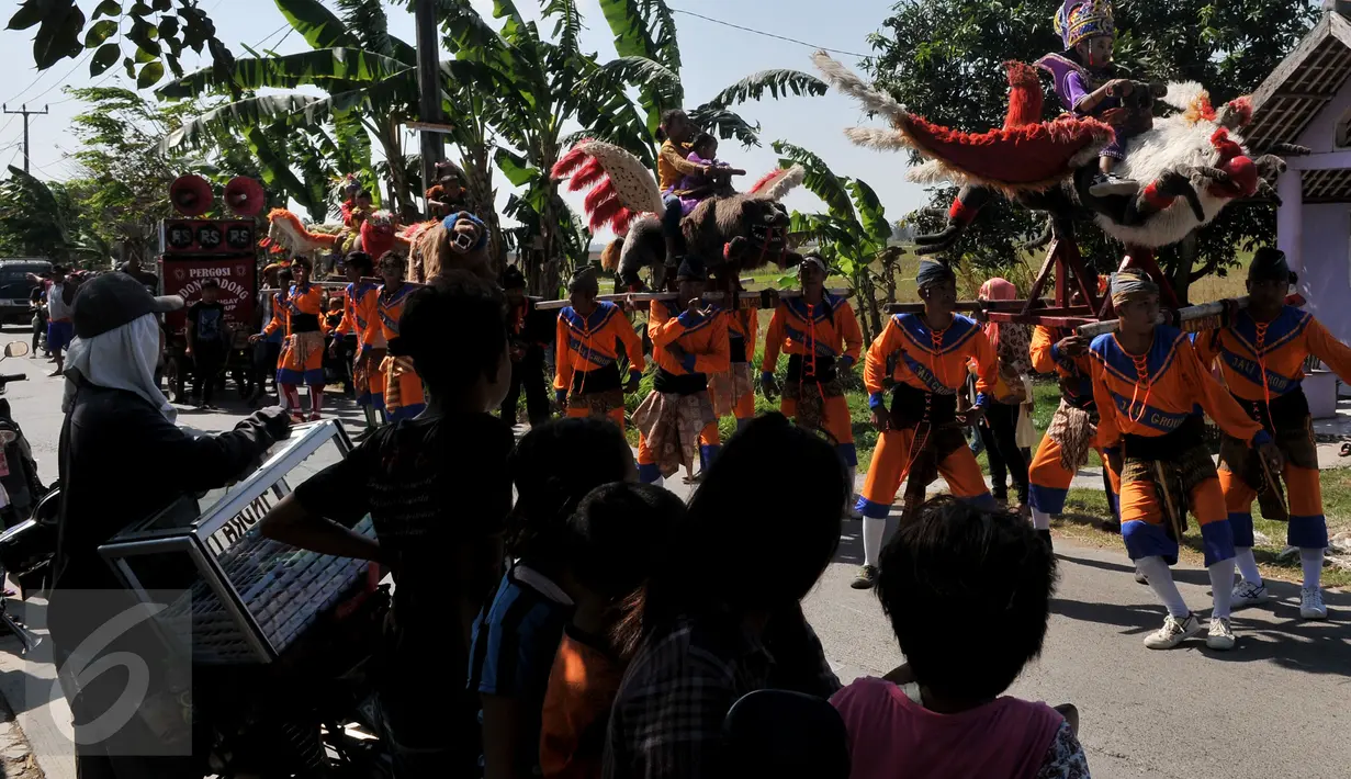 Para warga sekitar tampak melihat aksi dari pemain Sisingaan saat melewati ruas jalan di desa Jaya Bakti, Bekasi, Rabu (29/7/2015). Kesenian ini mempunyai ciri khas yaitu patung sisingaan atau binatang yang menyerupai singa. (Liputan6.com/JohanTallo)