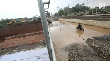 Pengendara motor melintasi genangan air di kawasan Kemiri Muka, Depok, Jawa Barat, Senin (2/10). Buruknya sistem drainase menyebabkan air selalu menggenang setiap musim hujan sehingga mengganggu aktivitas warga. (Liputan6.com/Immanuel Antonius)