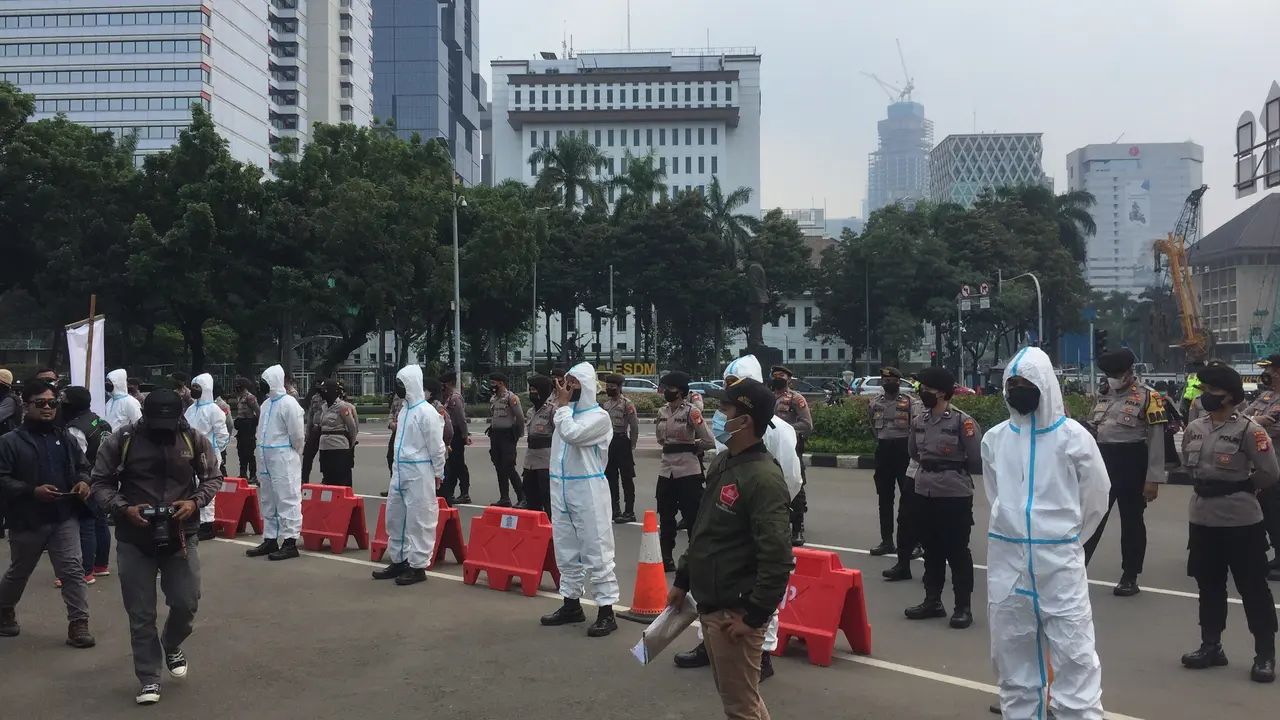 Aksi demonstrasi driver ojek online (ojol) di kawasan Patung Kuda Jakarta, dikawal sejumlah anggota polisi yang menggunakan baju hazmat.