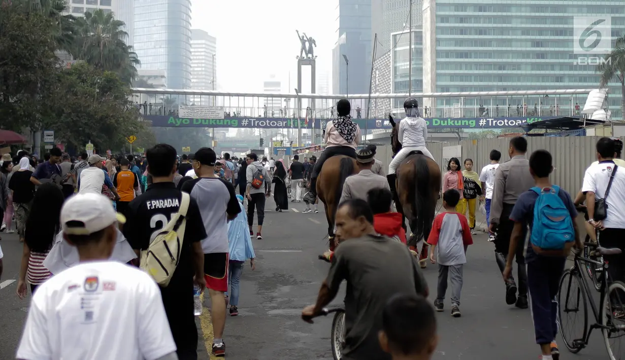 Pengunjung menunggang kuda milik satuan polisi berkuda Polda Metro Jaya di Bundaran HI, Jakarta, Minggu (18/3). Kuda-kuda itu diterjunkan untuk memberi pengenalan terhadap satuan polisi berkuda yang dimiliki Polda Metro Jaya. (Liputan6.com/Faizal Fanani)