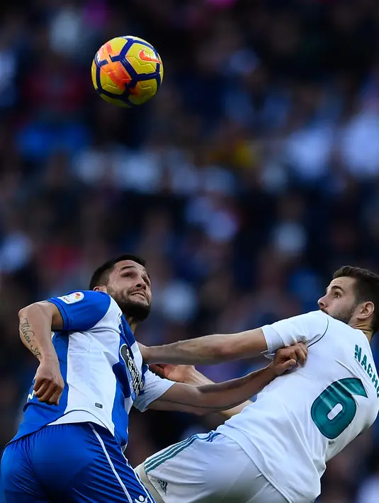 Pemain Real Madrid, Nacho Fernandez berebut bola dengan pemain Deportivo La Coruna, Florin Andone dalam lanjutan La Liga Spanyol di Santiago Bernabue, Senin (22/1). Real Madrid pesta kemenangan 7-1 atas Deportivo La Coruna. (OSCAR DEL POZO/AFP)