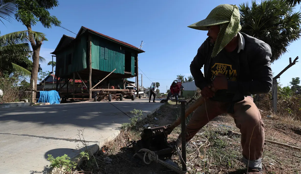 Seorang pria menarik rumah kayu ke tempat di desa Pon Sang di sisi utara Phnom Penh, Kamboja (26/4/2020). Ini adalah cara bergerak tradisional yang dikumpulkan oleh penduduk desa untuk saling membantu dengan menggunakan traktor dan batang kayu. dengan menjaga rumah tetap utuh. (AP/Heng Sinith)