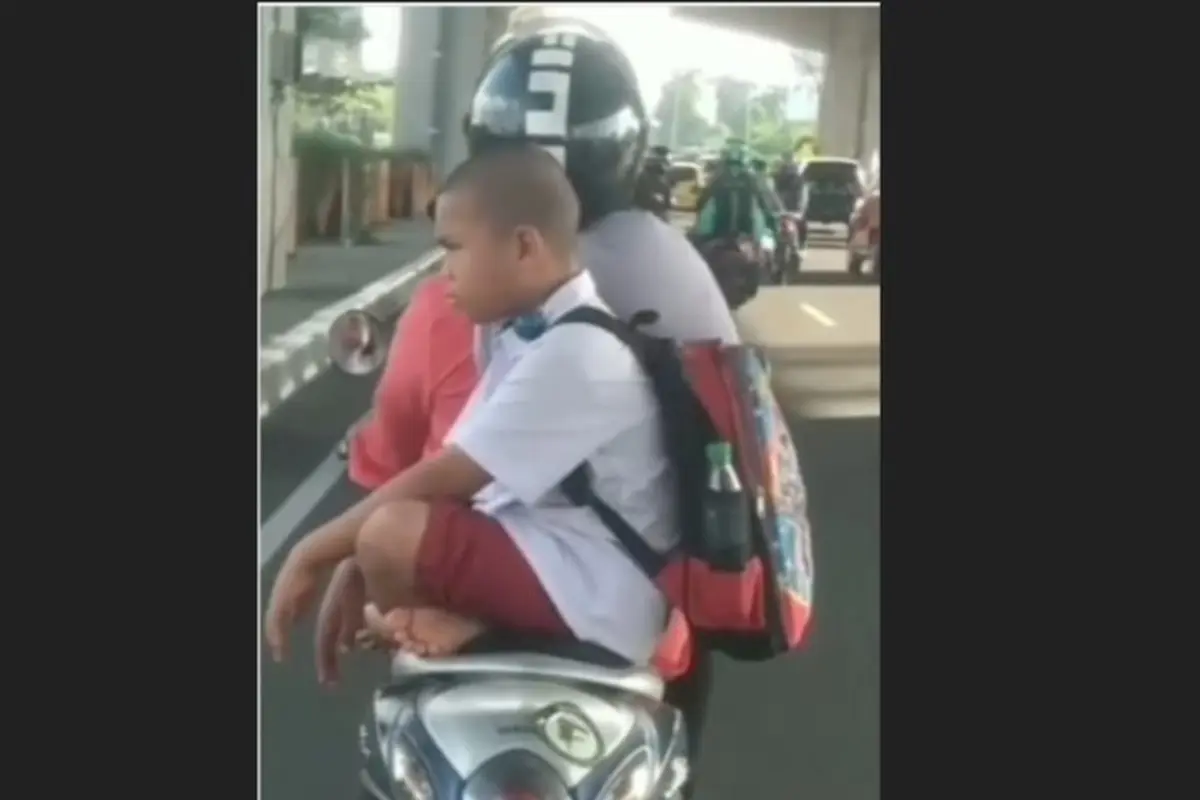Bocah SD duduk bersila saat diboceng motor. (capture/istimewa)