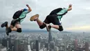 Penerjun Kanada Jeremy Bruns (kiri) dan Kelsey Fry (kanan) melompat dari dek terbuka Menara Kuala Lumpur saat International Tower Jump, Kuala Lumpur, Malaysia, 3 Februari 2023. Lebih dari 100 penerjun melompat dari Menara Kuala Lumpur setinggi 300 meter yang terkenal tersebut. (MOHD RASFAN/AFP)