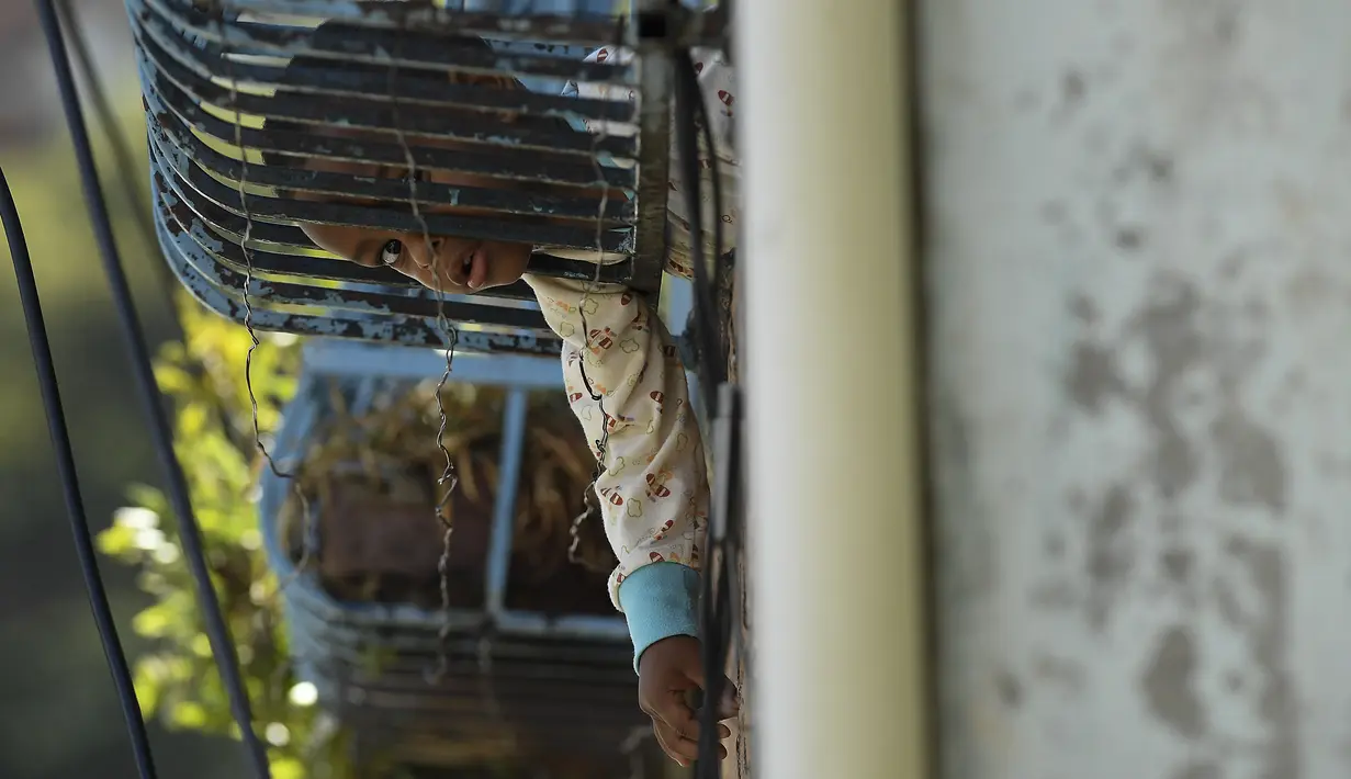 Anak-anak menonton warga memainkan permainan tradisional "chapitas" atau Caps, di lingkungan San Agustin Caracas, Venezuela, 29 Januari 2022. Permainan populer mirip dengan bisbol ini dimainkan dengan tutup botol sebagai pengganti bola, dan tongkat sebagai pengganti pemukul. (AP/Matias Delacroix)