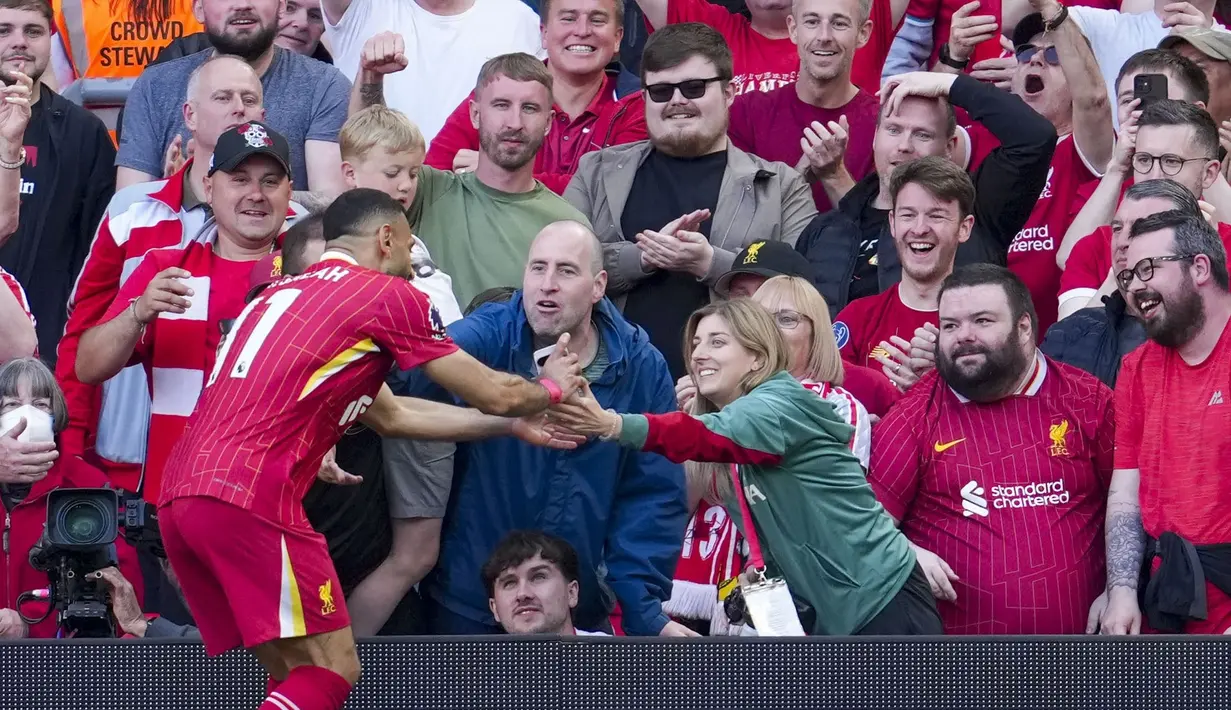 Pemain Liverpool, Mohamed Salah mengambil gawai dari salah satu suporter timnya untuk berswafoto setelah mencetak gol ke gawang Tottenham Hotspur dalam laga lanjutan Liga Inggris 2024/2025 di Anfiled, Liverpool, Inggris, Minggu (27/04/2025) waktu setempat. (AP Photo/Jon Super)