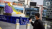 Pejalan kaki mengambil gambar Tugu Sepatu di Sudirman, Jakarta, Minggu (19/9/2021). Tugu Sepatu menjadi sasaran pencoretan dengan semprotan aerosol oleh orang tak dikenal sehari usai diresmikan pada 17 September 2021. (Liputan6.com/Faizal Fanani)