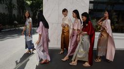 Para pekerja wanita mengenakan kostum tradisional berjalan untuk mengikuti upacara keagamaan Buddha sebagai persiapan festival tahun baru Songkran di luar kantor di Bangkok, Thailand (9/4). (AFP Photo/Romeo Gacad)