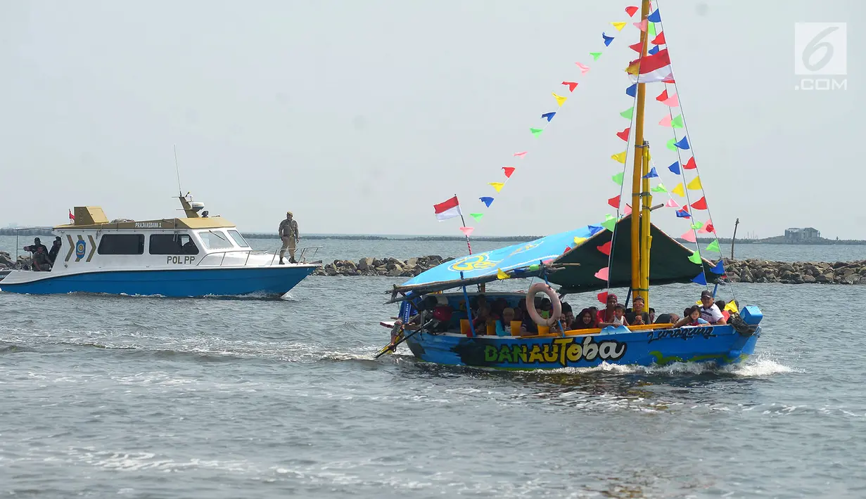 Wisatawan berkeliling menggunakan perahu wisata di Pantai Ancol, Jakarta, Senin (18/6). Taman Impian Jaya Ancol masih menjadi destinasi wisata yang ramai dikunjungi saat libur Lebaran. (Merdeka.com/Imam Buhori)